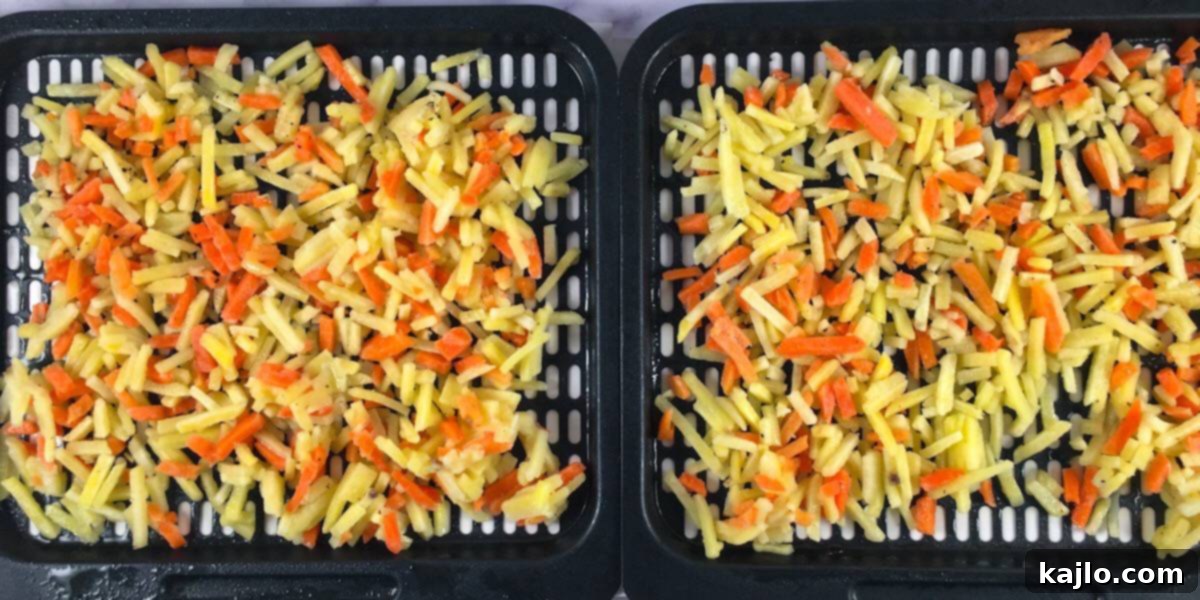 Uncooked frozen hash browns spread on an air fryer tray.