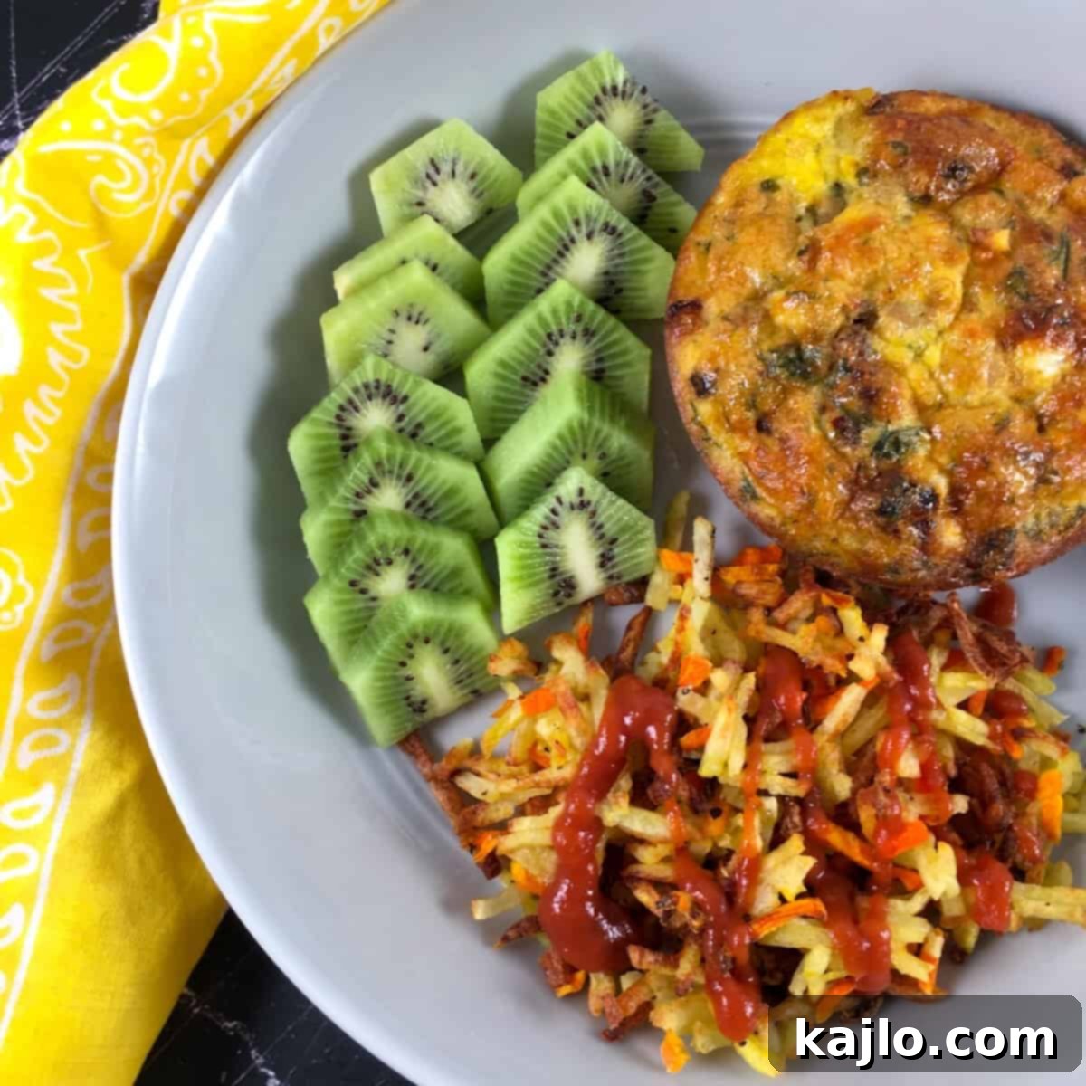 A breakfast meal featuring cooked hash browns, kiwi, and a frittata, showcasing a balanced meal.