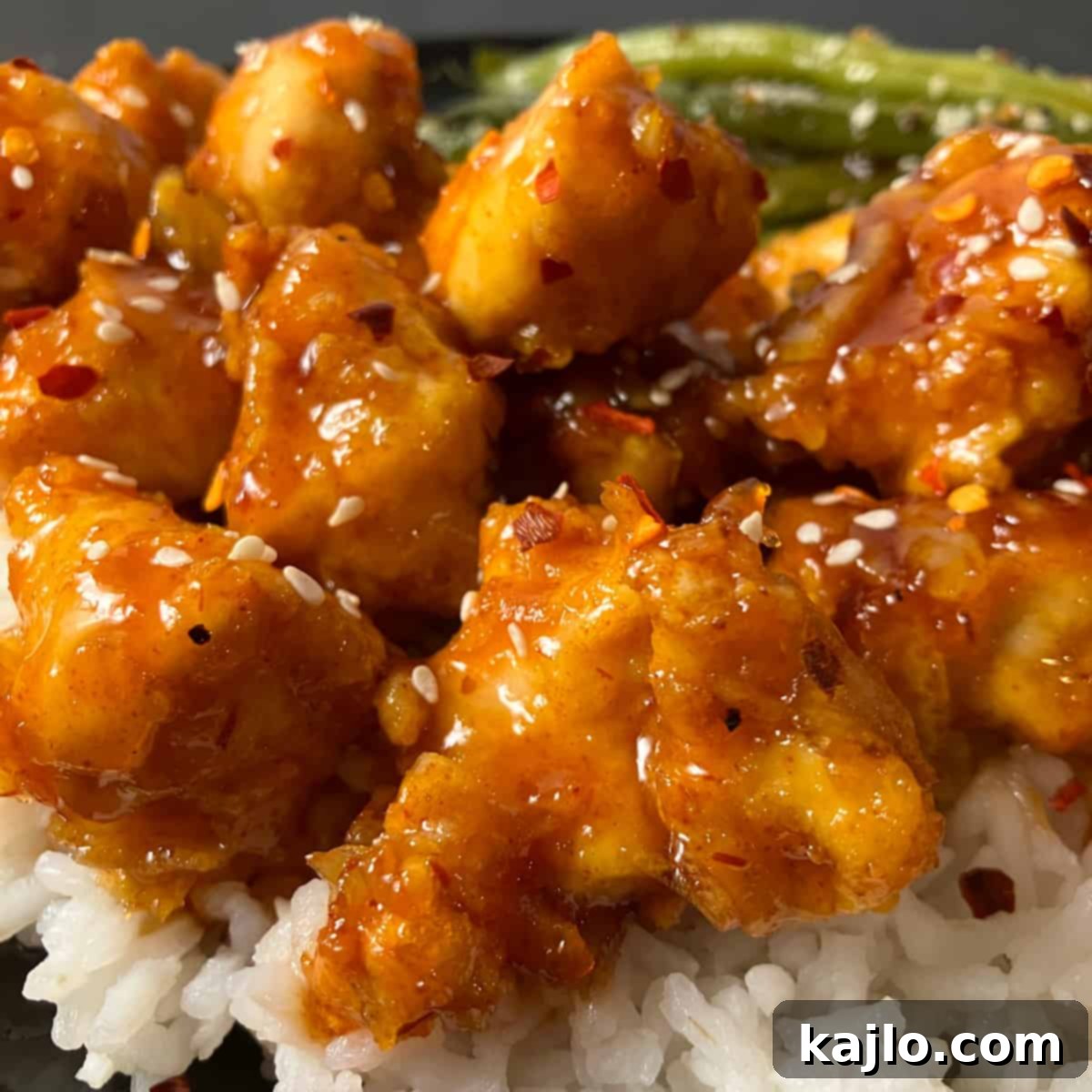 Crispy Air Fryer Orange Chicken coated in a sweet and sticky orange marmalade sauce, garnished with sesame seeds and green onions