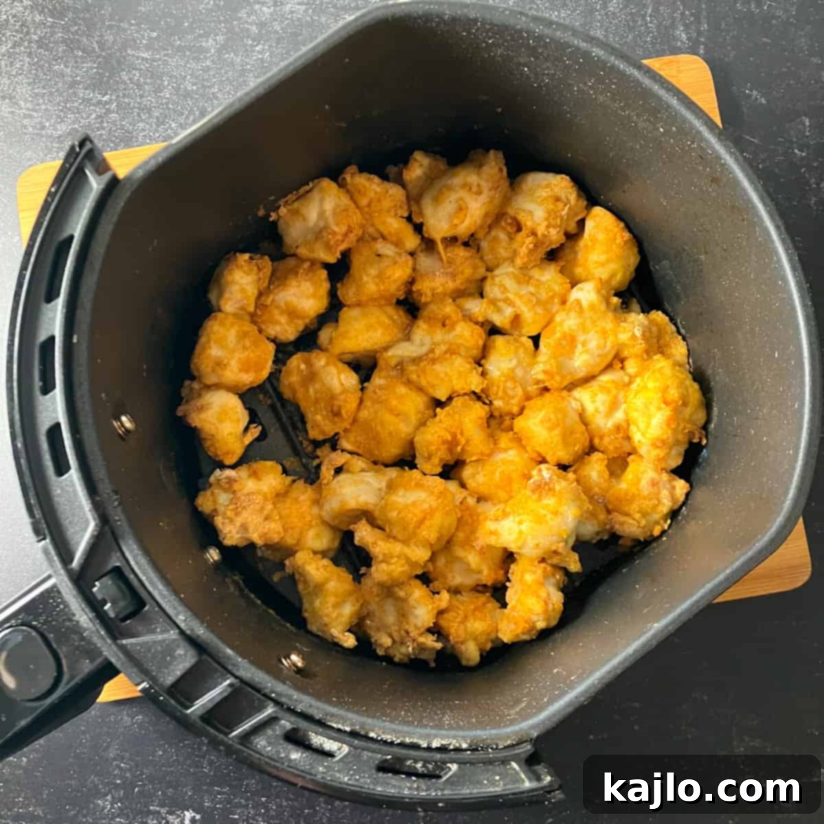 Chicken pieces cooking evenly in an air fryer basket, appearing golden and crispy