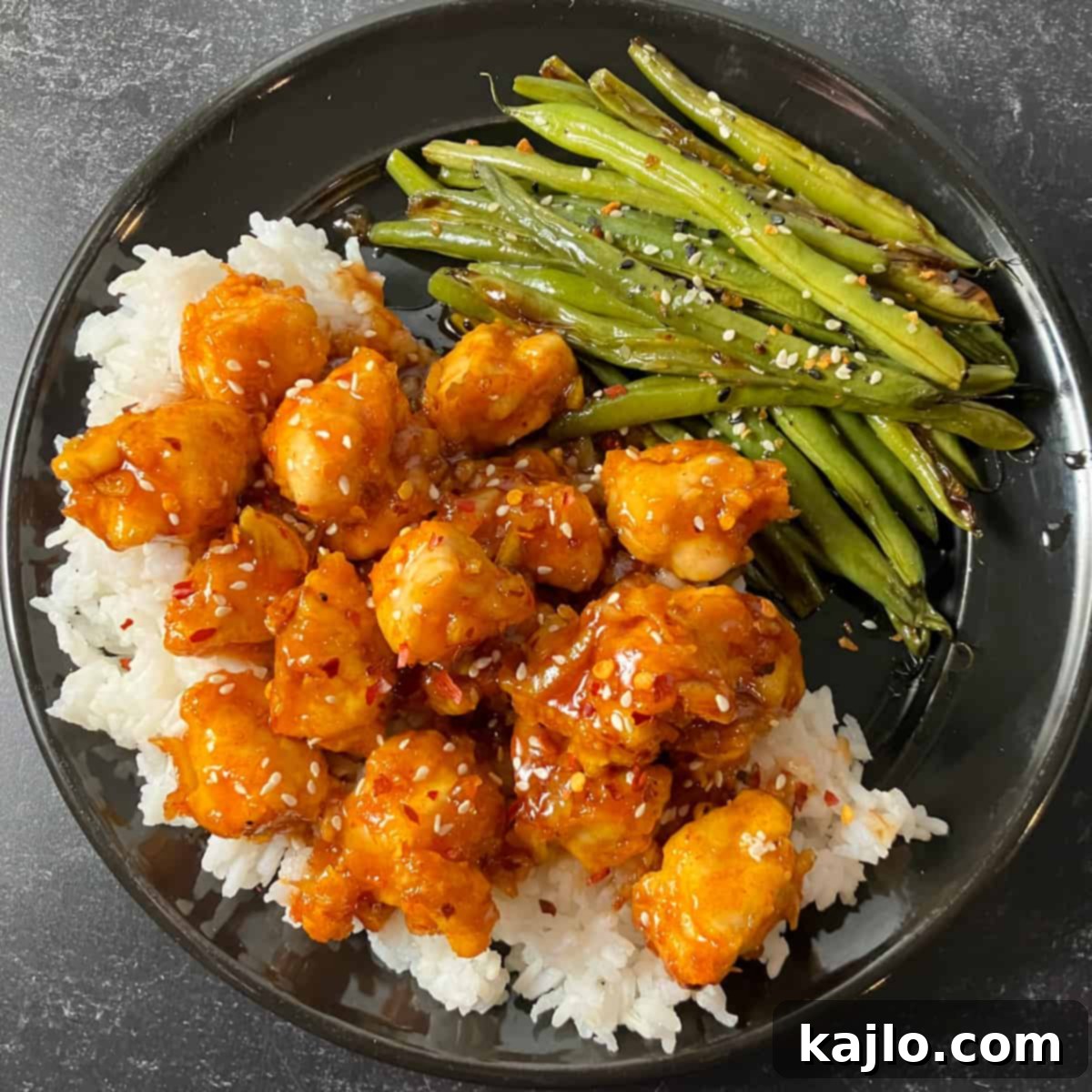 Closeup of air fryer orange chicken with orange marmalade, garnished with green onions