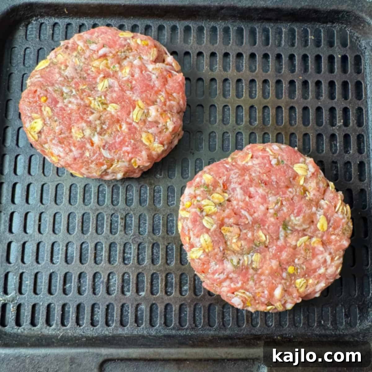 Sausage patty cooking in an air fryer basket, showing crispy edges