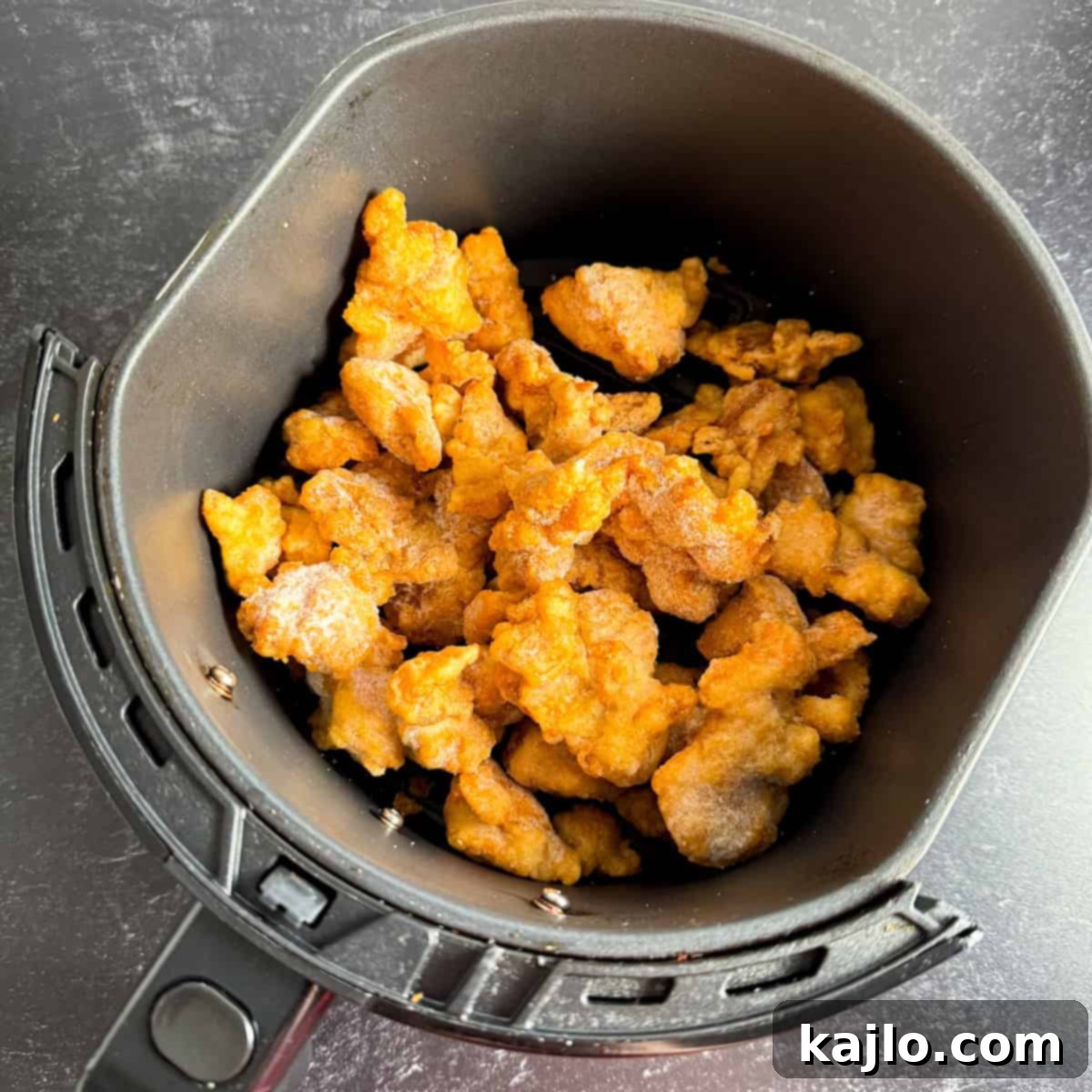 Frozen Chicken in Air Fryer Frozen Trader Joe's orange chicken pieces in an air fryer basket.