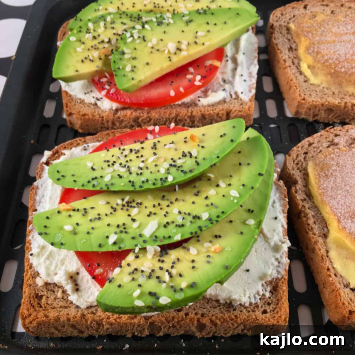 Air fryer avocado toast with a perfectly cooked fried egg on top, garnished with herbs.