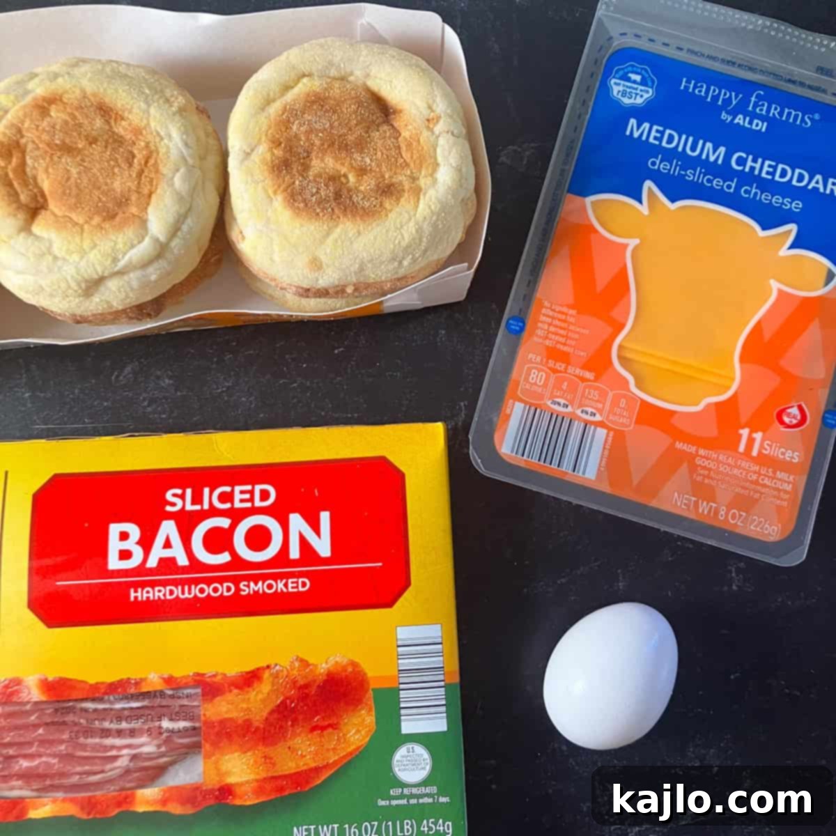 Ingredients for an air fryer breakfast sandwich: English muffin, egg, bacon, cheese, and cooking spray.