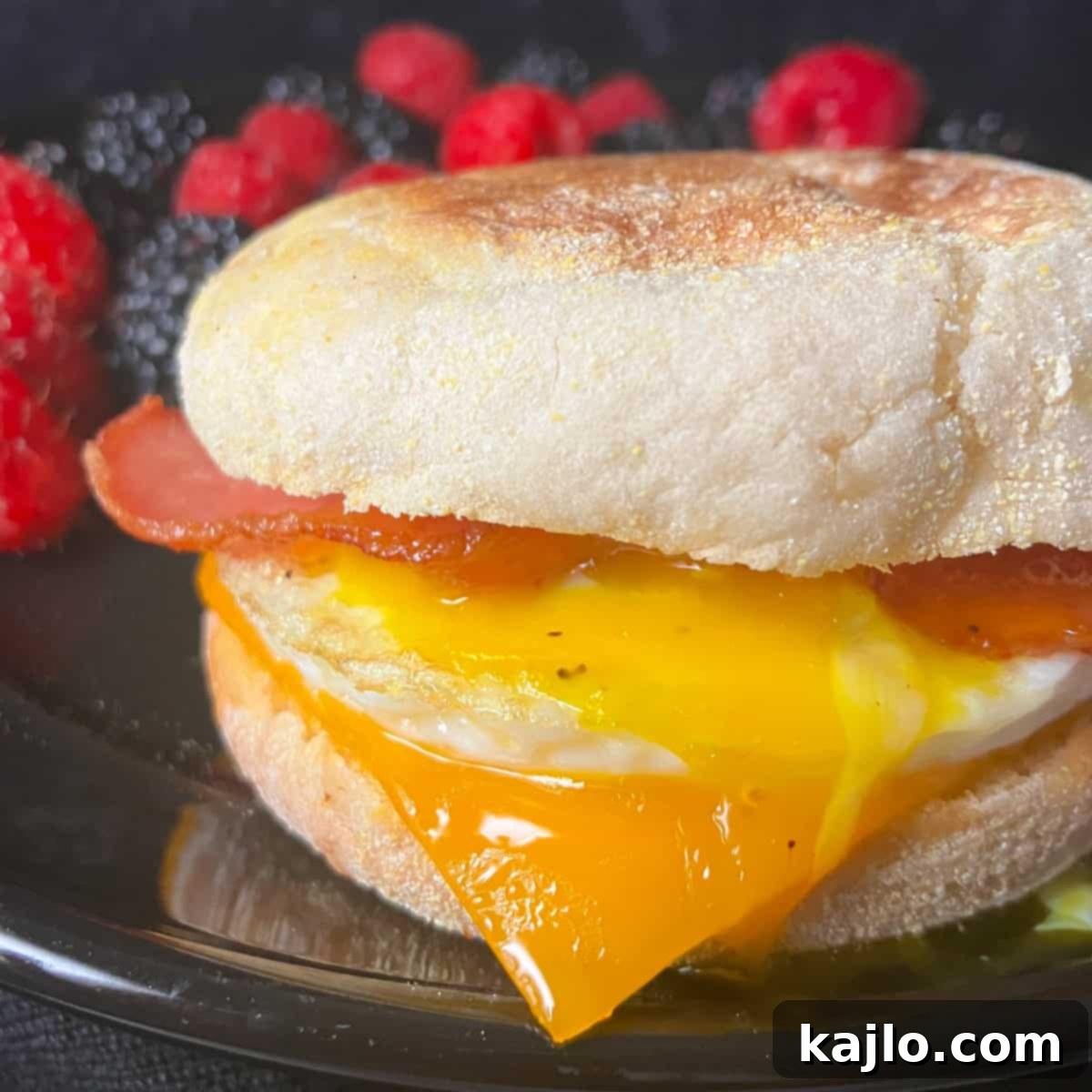 Assembled air fryer breakfast sandwich with egg, bacon, and melted cheese on an English muffin.
