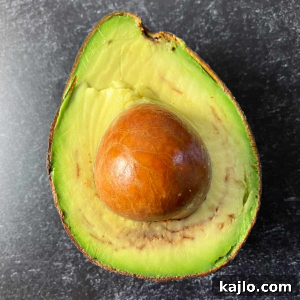 Spotty Avocado: Is It Still Good to Eat 3 Close-up of an avocado half showing distinctive brown spots and stringy vascular browning, a result of cold exposure.
