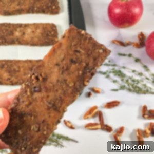Photo of bars of the ground turkey jerky recipe on a baking sheet, surrounded by thyme, apples, and pecans (square image)
