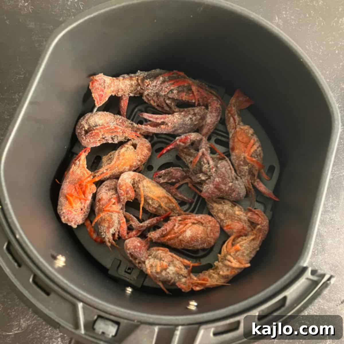Frozen crawfish arranged in an air fryer basket before cooking