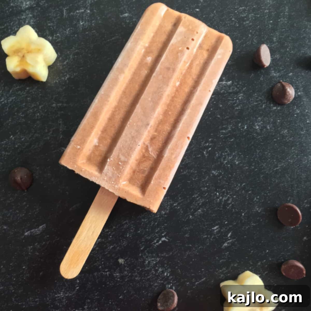 Sugar-Free Vegan Banana Popsicles 3 Two homemade sugar free banana popsicles on a wooden board, showcasing their creamy texture.