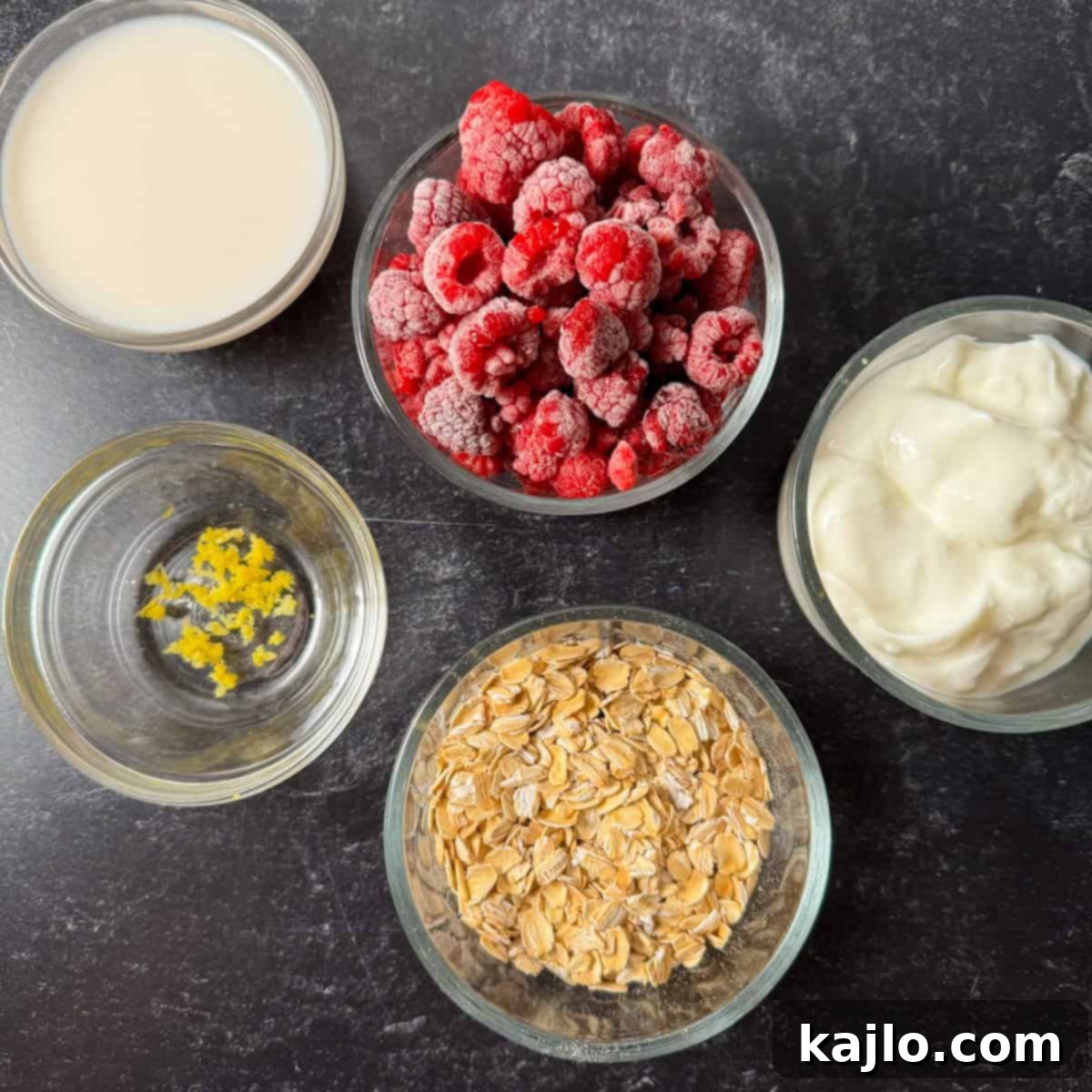 Overnight Oats: Your Favorite Frozen Fruit Creation 3 Display of fresh and frozen ingredients needed for overnight oats: oats, Greek yogurt, milk, frozen berries, and lemon zest.