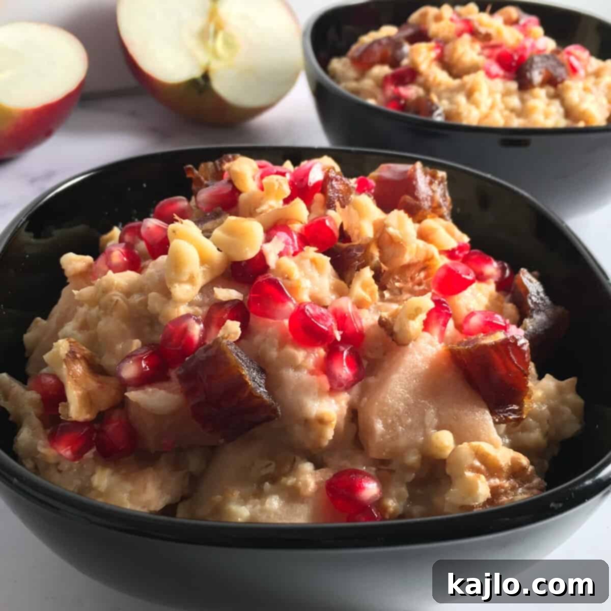 A bowl of apple spice oats topped with fresh pomegranate and dates.