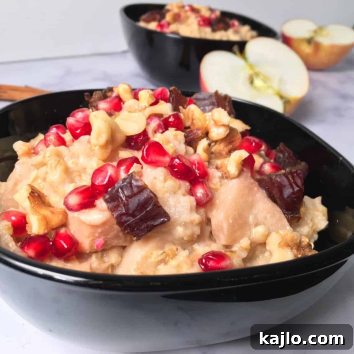 A close-up of a bowl of oatmeal topped with fresh pomegranate arils and chopped Medjool dates.