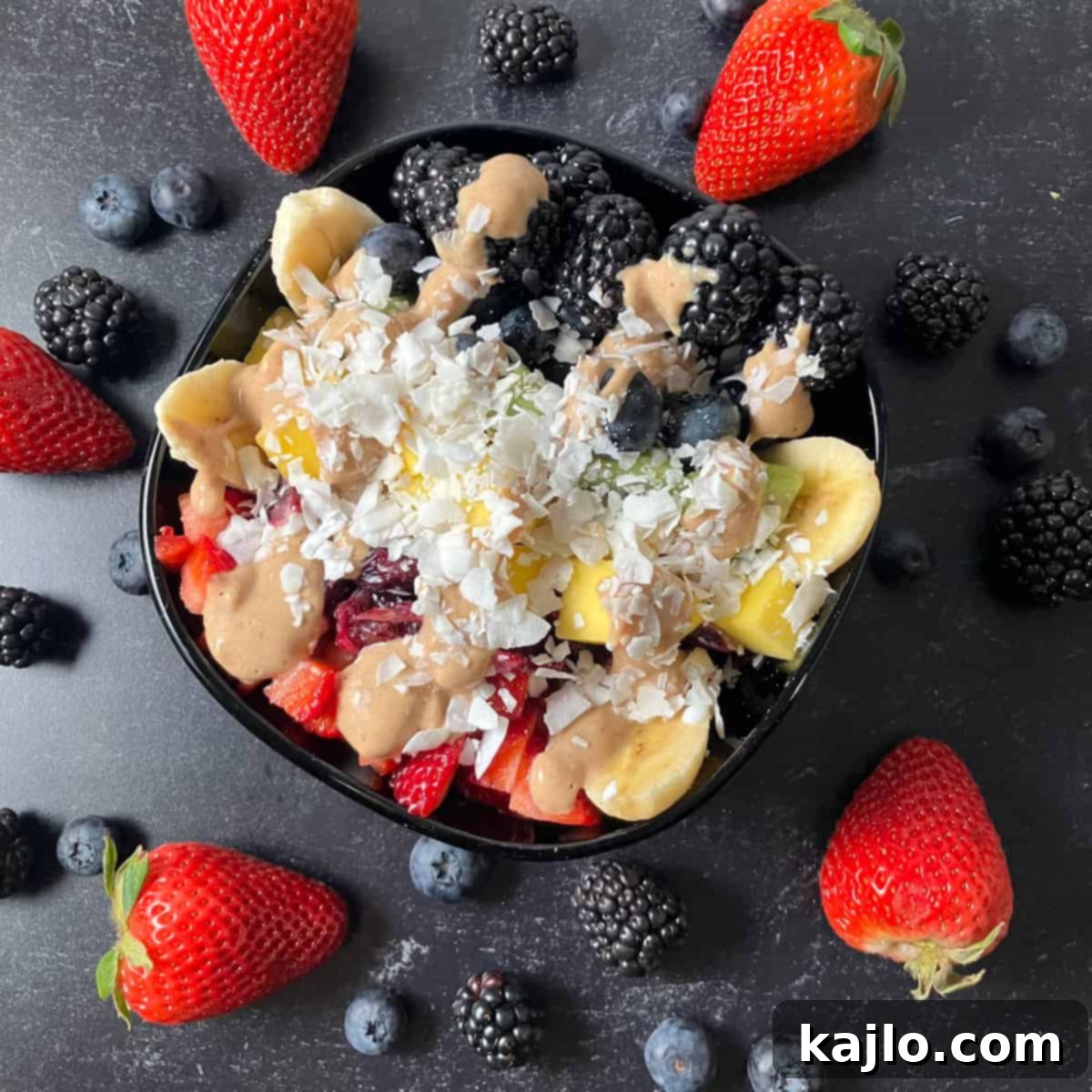 The World of B Fruits Over 40 Varieties Revealed 6 A vibrant breakfast bowl filled with sliced bananas, berries, and a drizzle of sauce.