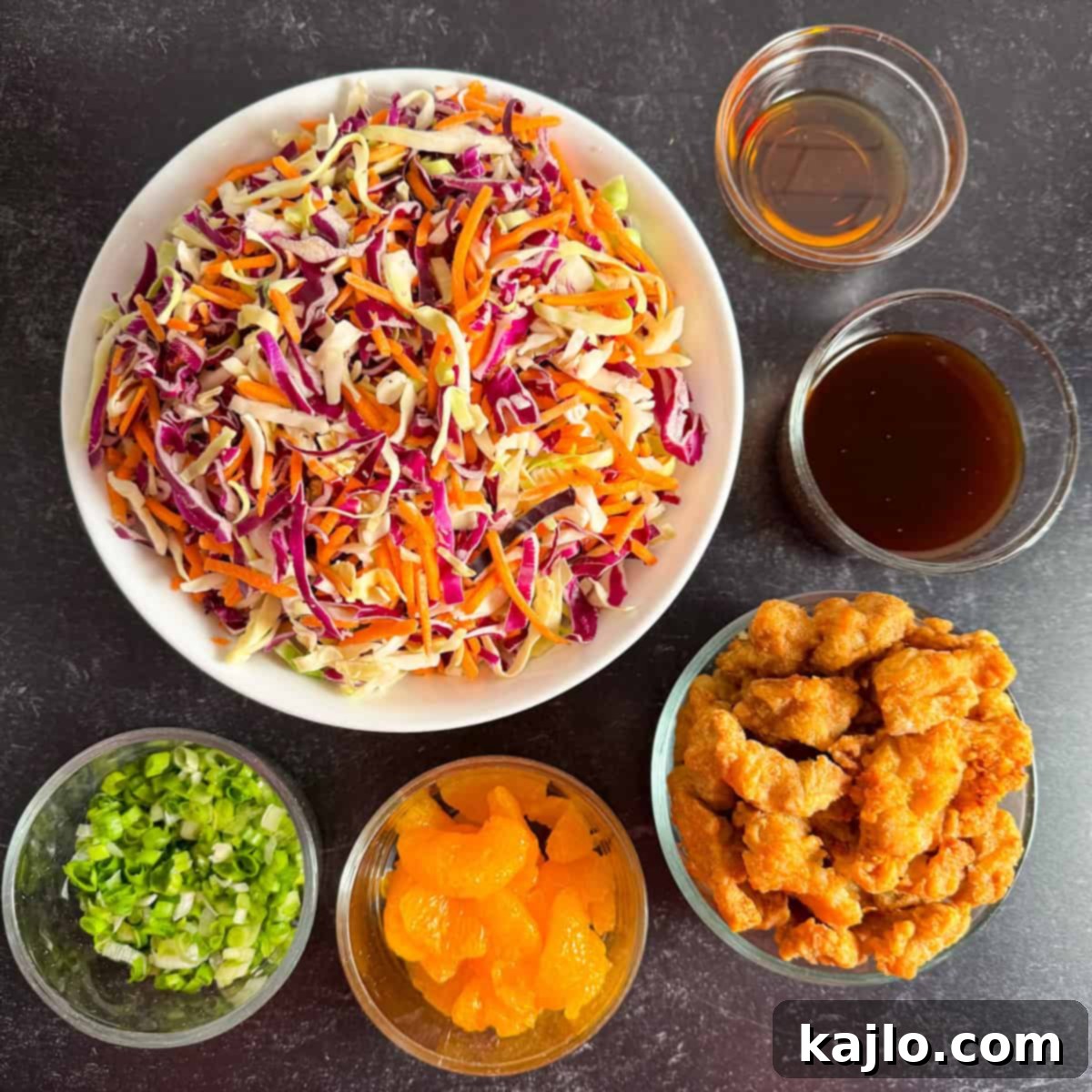 Zesty Orange Chicken Salad 3 All ingredients laid out for making orange chicken salad, including chicken, cabbage, mandarin oranges, and sauce.