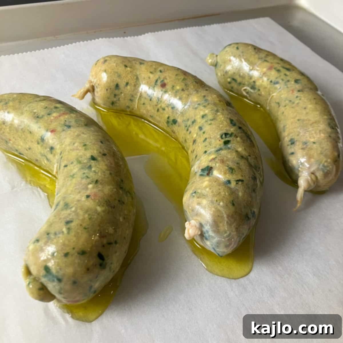 Homemade chicken sausage links drizzled with olive oil on a baking sheet, ready for the oven