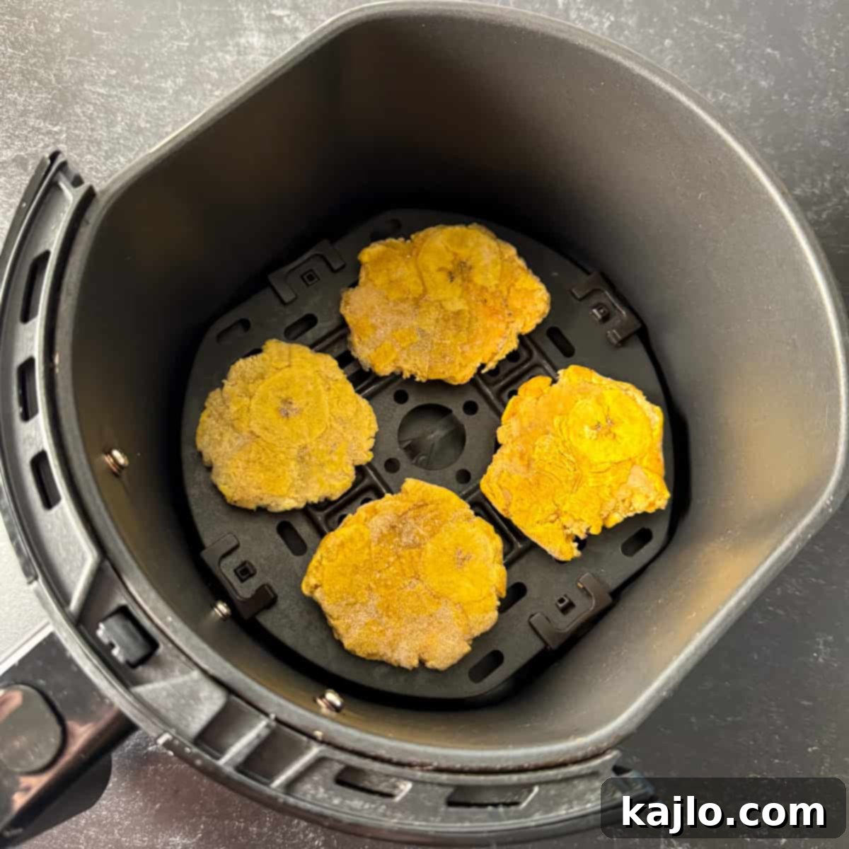 Air Fried Frozen Plantains Sweet Maduros and Savory Tostones 6 Frozen tostones cooking in an air fryer, showing a light golden crust forming.