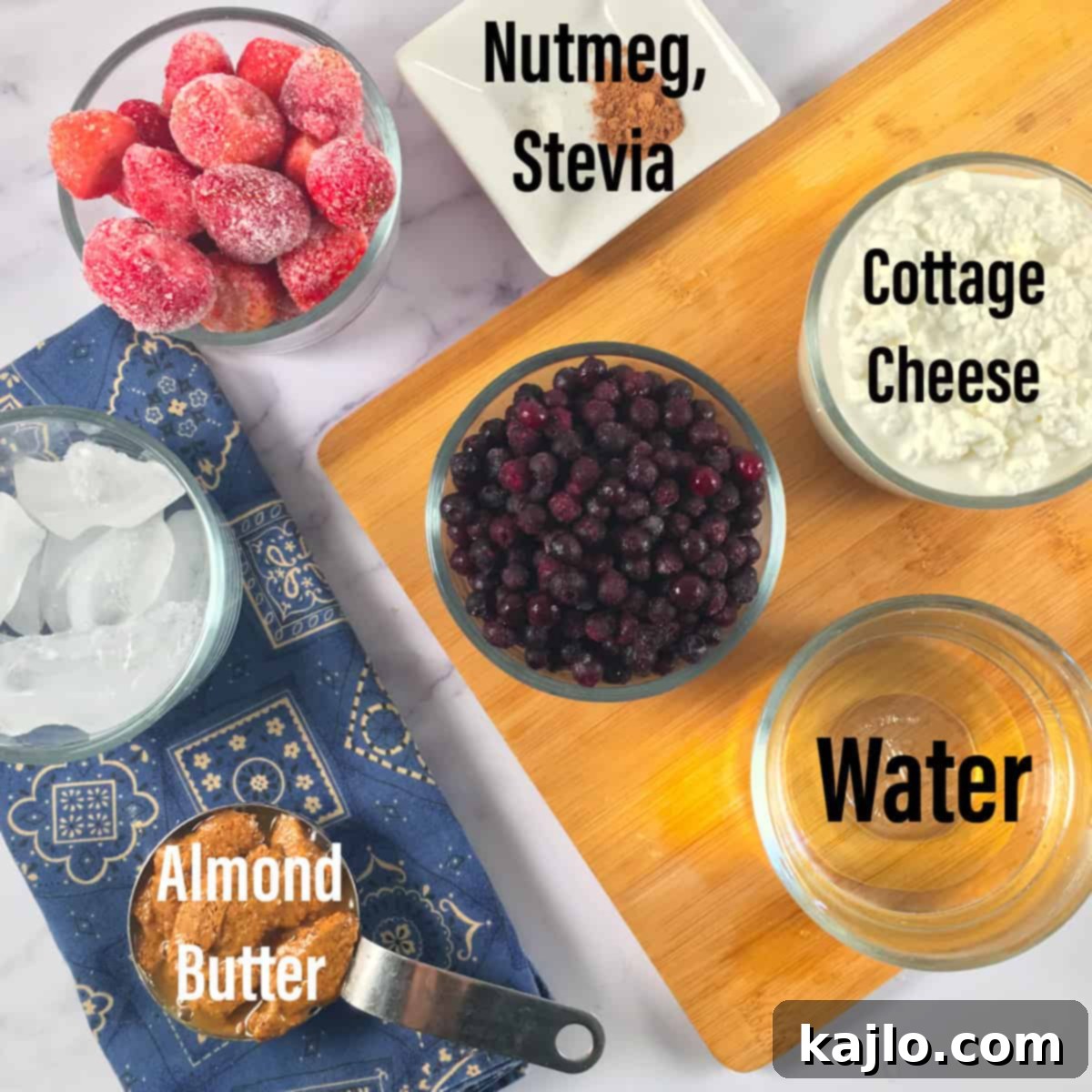 All the keto blueberry smoothie ingredients laid out, including cottage cheese, frozen berries, almond butter, and spices.
