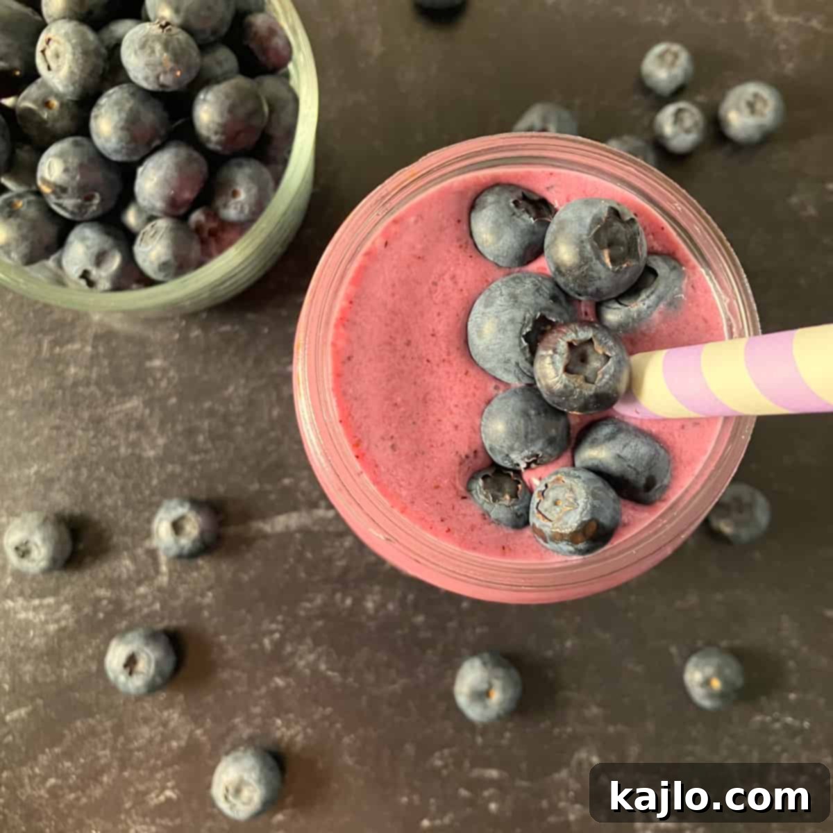 Beautifully blended peach blueberry smoothie in a glass with a straw