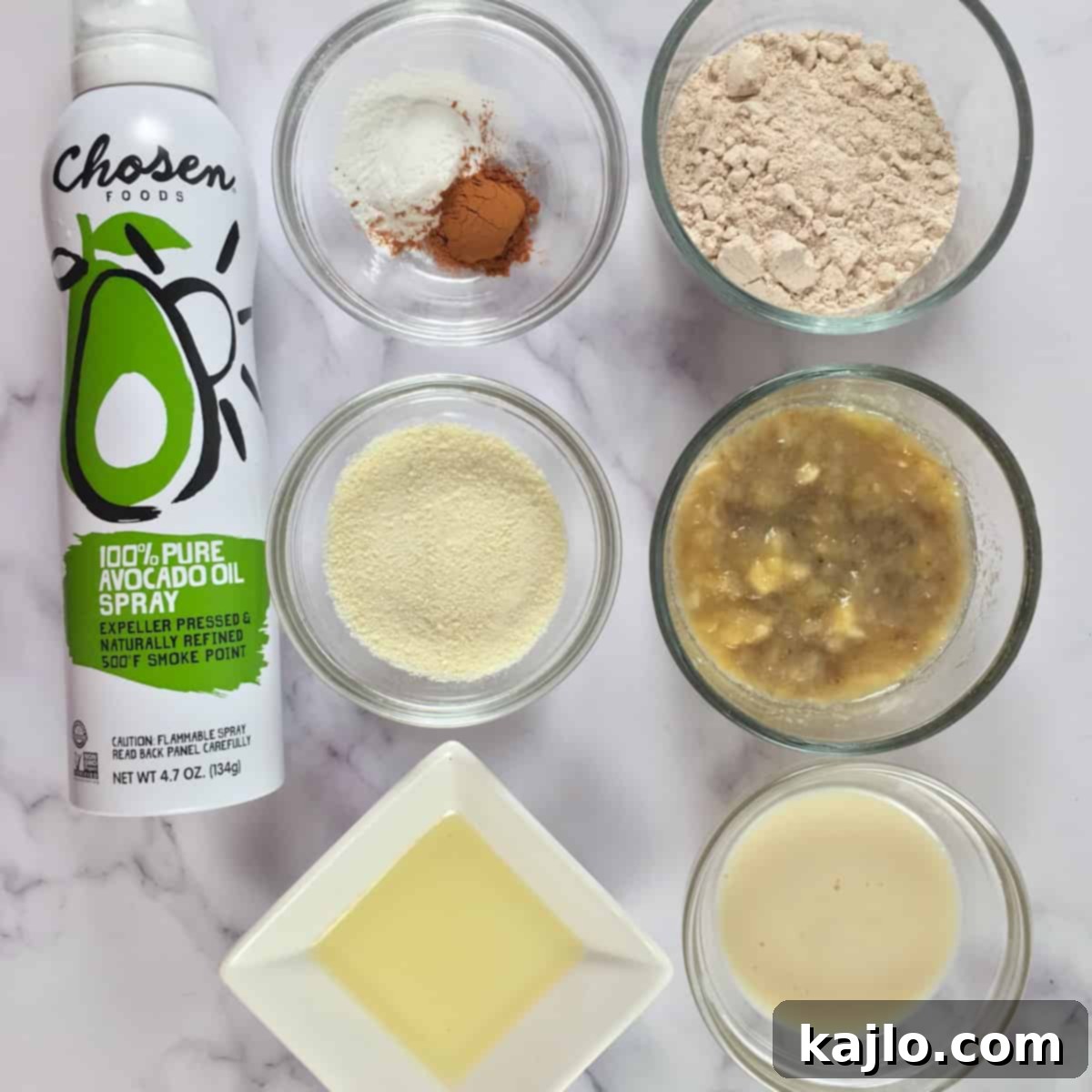 Collection of ingredients for air fryer muffins: ripe bananas, flour, milk powder, milk, oil, baking powder, cinnamon, and cooking spray