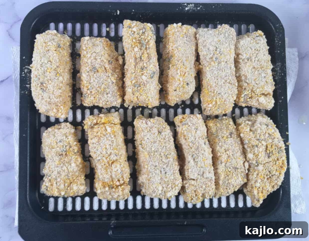 Uncooked breaded fish sticks on an air fryer tray